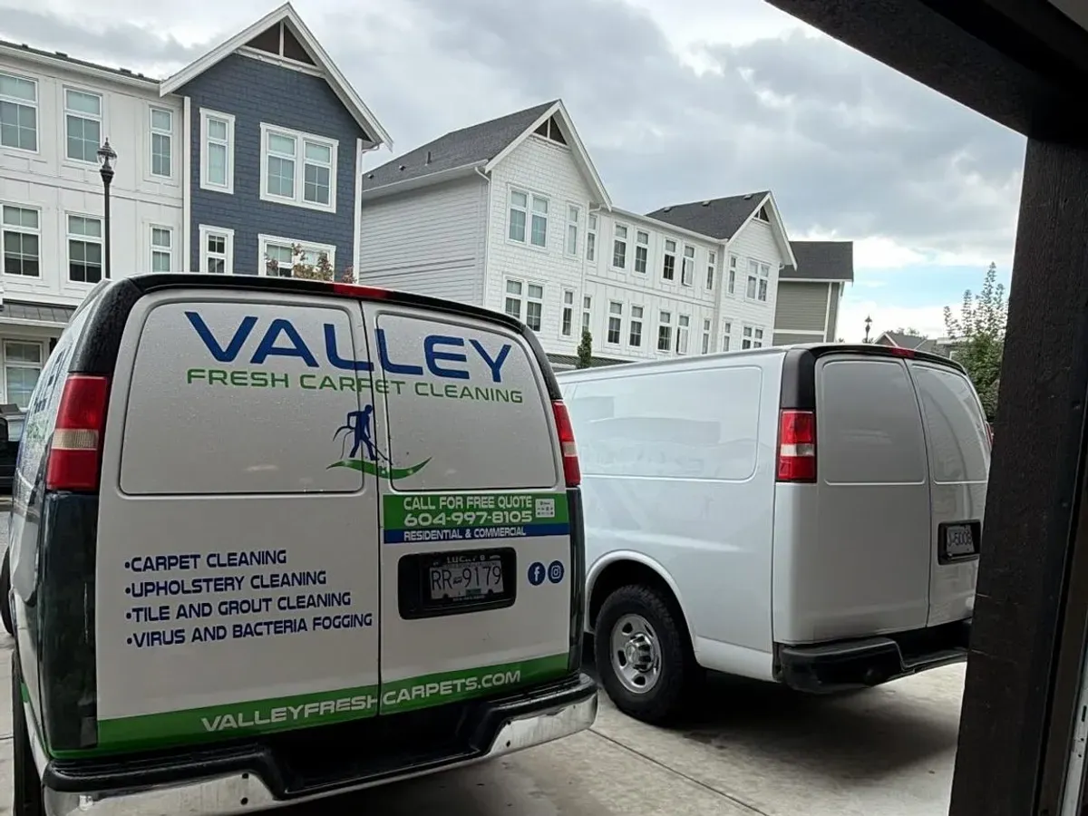 Two Valley Fresh Carpet Cleaning vans parked outside a row of newer townhomes in Abbotsford