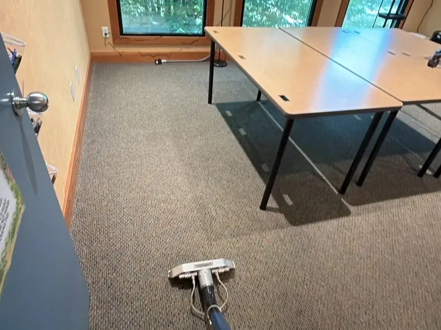 Extraction wand cleaning commercial carpet in an office meeting room