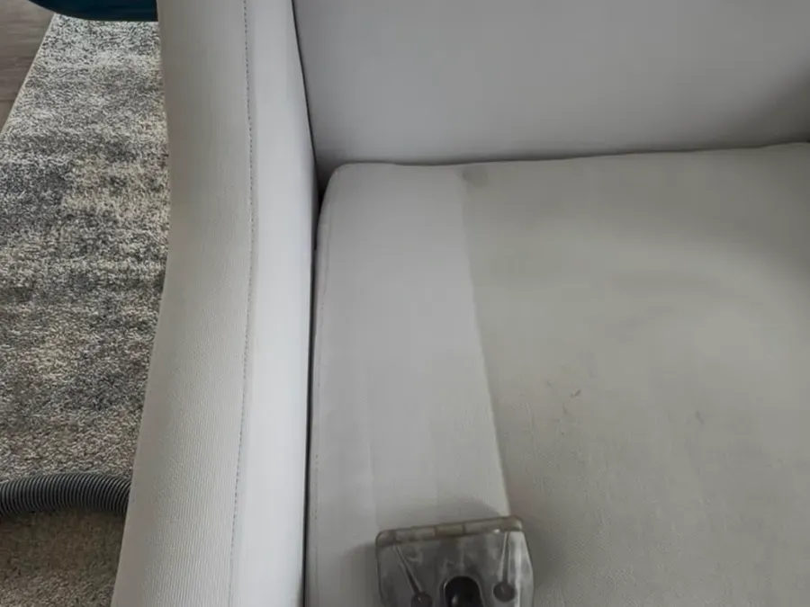 Upholstery extraction wand cleaning a white fabric chair
