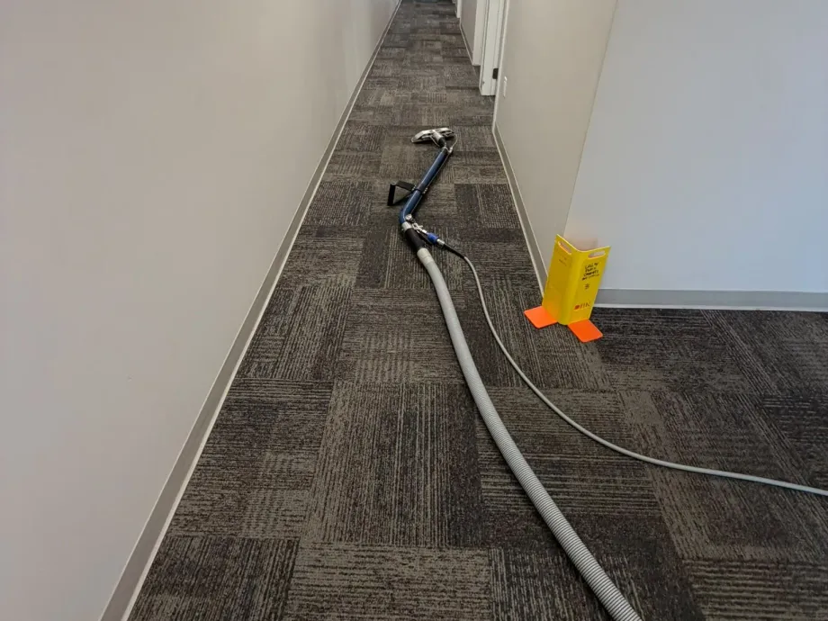 Truck-mount extraction wand and hose lines running down a strata corridor in Chilliwack